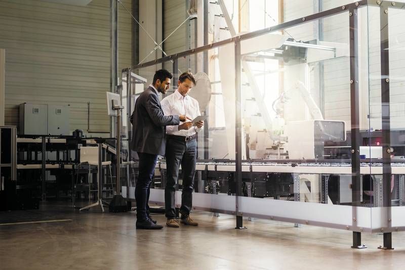 Two businessmen with tablet talking in modern factory