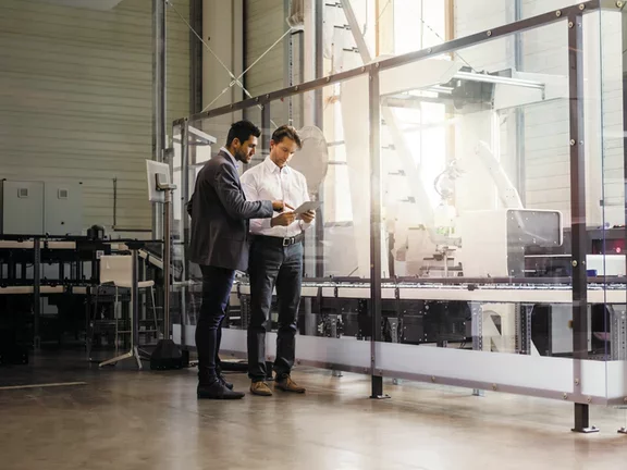 Two businessmen with tablet talking in modern factory